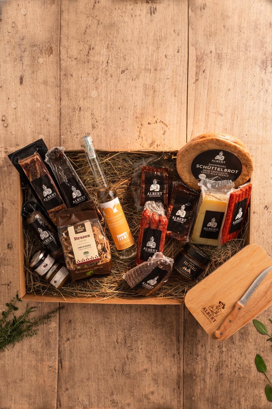 Große Holzkiste mit Schnaps, Struzen, Honig, Speck, Käse, Schüttelbrot und Speckbrettl mit Messer